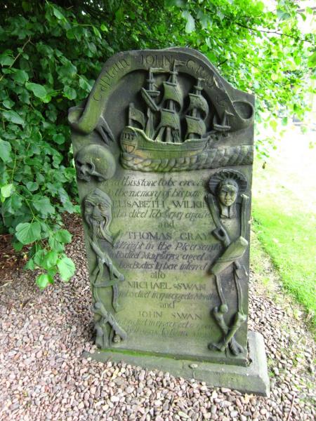 Ornate headstone of a Sea Captain and family, with carvings of a boat, rope, instruments as well as skull and bones